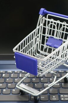 A mini shopping cart placed on a laptop keyboard, symbolizing online shopping and digital retail.